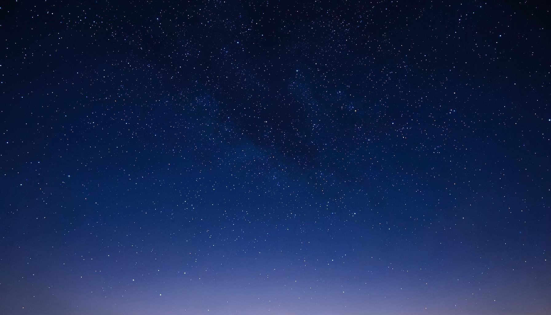 A calm night sky scattered with stars, deep navy blue fading into soft indigo at the horizon, evoking wonder and the human search for meaning